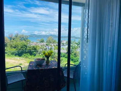 a table with a vase of flowers on a window at Aristo 2 Condo with a sea view in Surin Beach