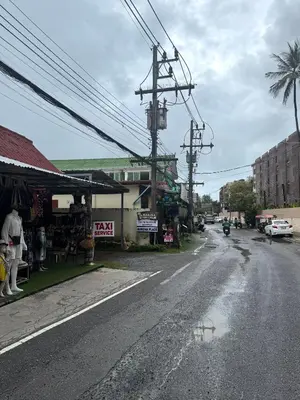 an empty street in a town with a palm tree at The Pinda House Bangtao in Bang Tao Beach