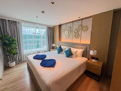 a bedroom with a large bed with blue pillows on it at La Vita 5 star Super 1 Bdr Nai Harn Beach in Rawai Beach