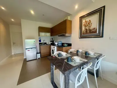 a kitchen with a table with chairs and a refrigerator at The Lago Nai Harn 2 BR-Walk to beach by ALL HOMES in Rawai Beach