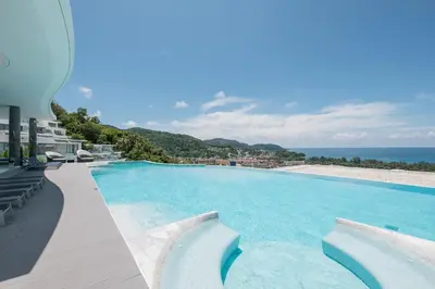 a large swimming pool with a view of the ocean at The View Phuket By RESAVA in Kata Beach