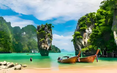 two boats on a beach with cliffs in the water at xx GO INN Patong Beach Phuket - โก อินน์ หาดป่าตอง ภูเก็ต in Patong Beach