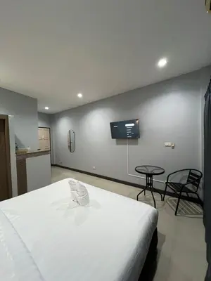 a bedroom with a white bed and a tv on the wall at PMS Guest House Patong in Patong Beach