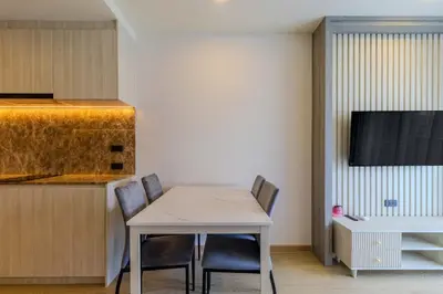 a kitchen with a table and chairs and a tv at C240 New Prime Location 1BR Condo Near Beach Club in Thalang