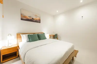 a white bedroom with a bed and a painting on the wall at Nai Harn Beach Holiday Home - Rawai 4bdr in Rawai Beach