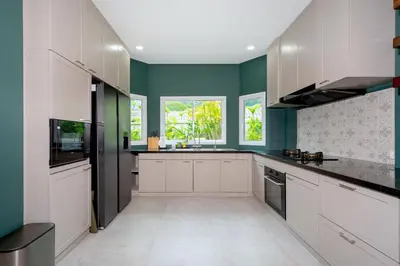 a kitchen with white cabinets and green walls at Exclusive & Private! Elegant Two-Storey Pool Villa Anong in Kamala in Kamala Beach