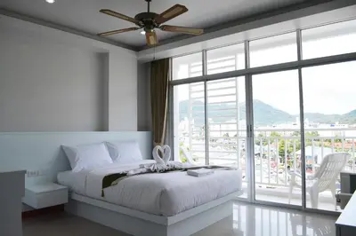 a bedroom with a bed and a large window at Angelina Guesthouse in Patong Beach