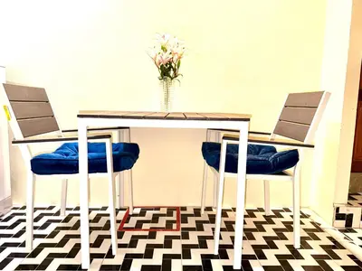 a table with two chairs and a vase with flowers at Vista Inn Patong in Patong Beach