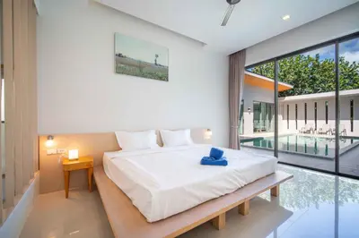 a bedroom with a bed and a large window at Elm pool villa Phuket in Kata Beach