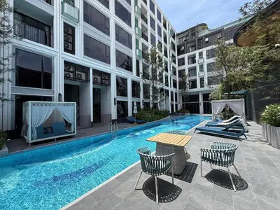 a swimming pool in a building with a table and chairs at Новая студия Bellevue Bangtao in Laguna Phuket