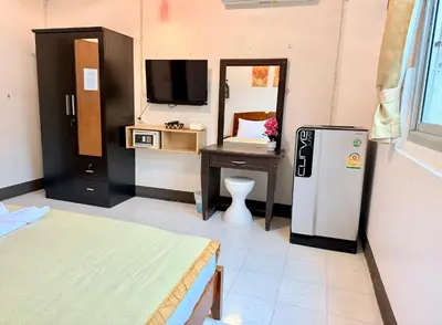 a room with a refrigerator and a desk and a tv at Om Sab House Patong in Patong Beach