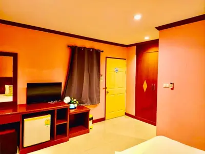 a living room with a television and a yellow door at Hotel Hollywood Inn Love Patong in Patong Beach