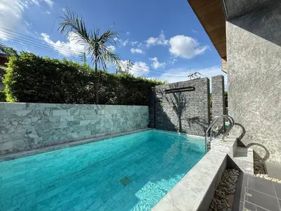 a swimming pool in a backyard with a stone wall at 2 Bedroom Pool Villa Chalong in Chalong
