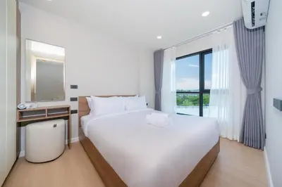 a bedroom with a large white bed and a window at Cosy 1 bedroom apt at Space Cherngtalay - 402 in Bang Tao Beach