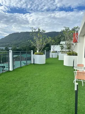 a balcony with green grass and white fences at FantaSea Kamala By Ere in Kamala Beach