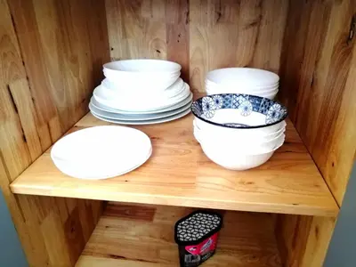a wooden shelf with white bowls and plates on it at Relife apartments Большая квартира с панорамным видом на горы на Най Харне in Phuket Town
