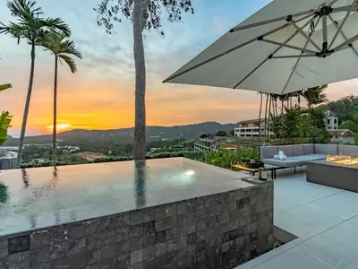 a swimming pool with an umbrella and a sunset at NEW Luxury 4BR Villa in Layan - Villa Zuma in Layan Beach