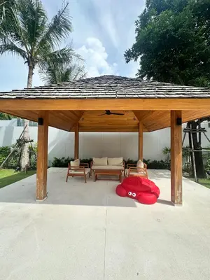 a wooden gazebo with a red pillow under it at Anchan Tropicana By Ere in Ban Phru Champa