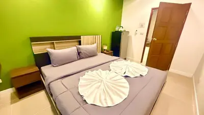 a green bedroom with a bed with two pillows at Abdullah Residence in Patong Beach