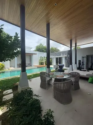 a patio with a table and chairs and a pool at Luxury Botanica Foresta 4 bed in Ban Phru Champa