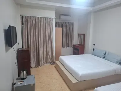a bedroom with a white bed and a television at Kami Guest House Patong in Patong Beach