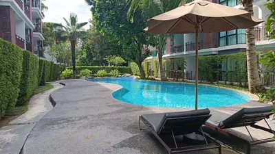 a swimming pool with two chairs and an umbrella at The Title Rawai Beach Front 1bdr in Rawai Beach