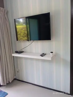 a flat screen tv on a wall with a shelf at The Title Rawai Beach Front 1bdr in Rawai Beach