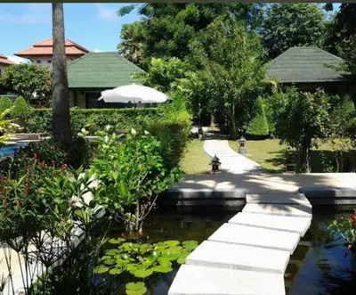 a walkway over a pond in a garden at Rawai Boutique Resort in Rawai Beach