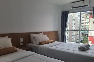 two beds in a room with a window at Wow Boutique Patong in Patong Beach