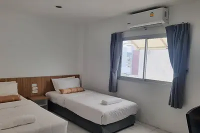 a small bedroom with two beds and a window at Wow Boutique Patong in Patong Beach