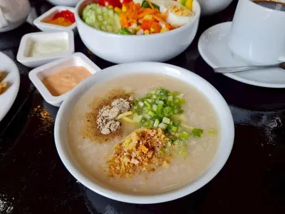 a bowl of soup with vegetables and other bowls of food at The Par Phuket Hotel in Kathu