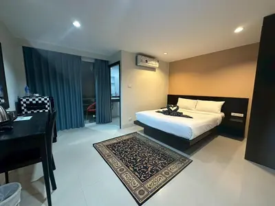 a bedroom with a bed and a desk and a bed and a table at Patong gray house in Patong Beach