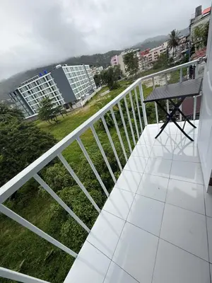 a balcony with a table and a view of buildings at Cha Cha Guesthouse in Patong Beach