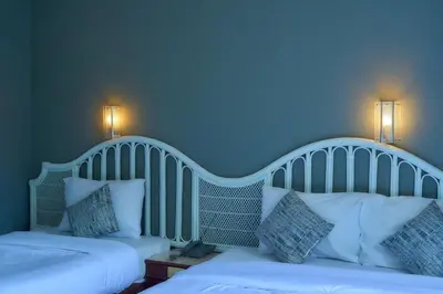 two beds in a room with a blue wall at Nora Bukit Hotel in Ban Sam Kong