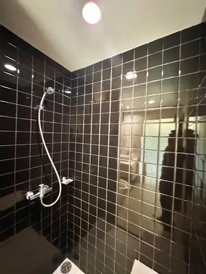 a bathroom with a black tiled wall with a shower at Pingping&FamilyAonang-2 in Ban Khlong Son