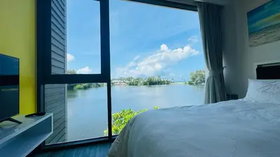 a bedroom with a large window with a view of a river at Cassia Sea and Pool view 2bd apartments by Aster in Laguna Phuket