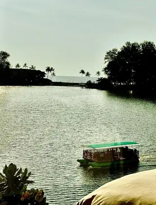 a boat on a river with palm trees in the background at Cassia Sea and Pool view 2bd apartments by Aster in Laguna Phuket