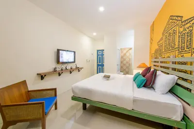 a bedroom with a bed and a chair and a television at The Pho Thong Phuket in Phuket Town