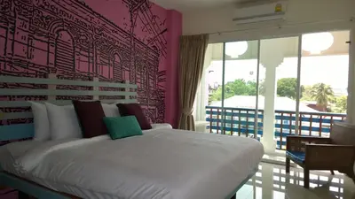 a bedroom with a white bed with a pink wall at The Pho Thong Phuket in Phuket Town