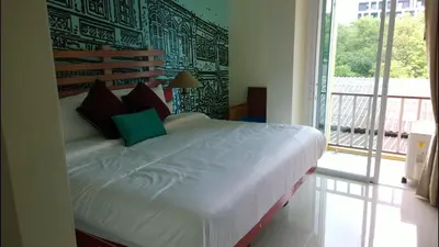 a bedroom with a large bed with a large window at The Pho Thong Phuket in Phuket Town