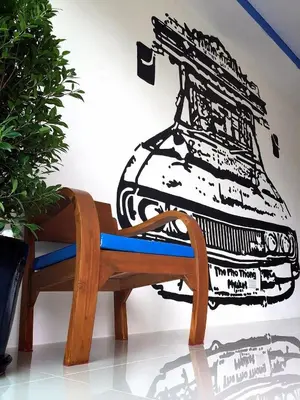 a bench with a drawing of a machine on the wall at The Pho Thong Phuket in Phuket Town