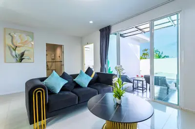 a living room with a black couch and a table at Exclusive! 3-Bedroom Pool Villa with Bay View-Nariya V8 in Chalong