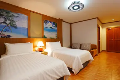 a hotel room with two beds and a clock on the wall at Chabana Resort Bang-tao Beach Phuket- SHA Extra Plus in Bang Tao Beach