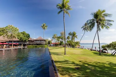 a pool at a resort with palm trees and the ocean at The Vijitt Resort - Deluxe Beachfront Villa in Ban Saiyuan (1)