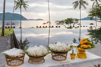 a table with three baskets of flowers on it next to the water at The Vijitt Resort - Deluxe Beachfront Villa in Ban Saiyuan (1)