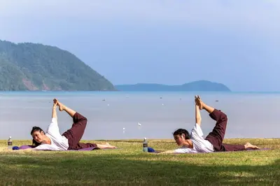 a group of people doing yoga on the grass by the water at The Vijitt - Two Bedroom Pool Villa in Ban Saiyuan (1)