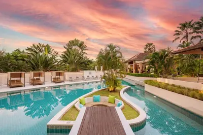 a pool at a resort with a table and chairs at Naiyang Villa in Nai Yang Beach