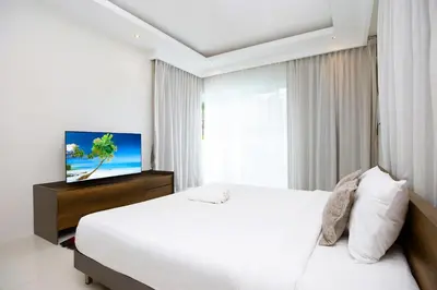 a bedroom with a white bed and a flat screen tv at 2 Bedroom Villa Janine with Private Pool and Rooftop terrace in Kamala Beach