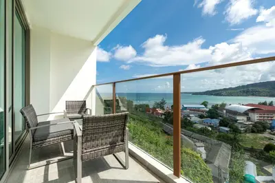 a balcony with a table and chairs and a view of the ocean at Elegant 2BR Oceanview Condo Oceana C73 - 5 min walk Kamala Beach in Kamala Beach