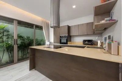 a kitchen with a counter and a large window at Villa Mauri – Modern 3BR Villa with Private Pool in Kata Beach
